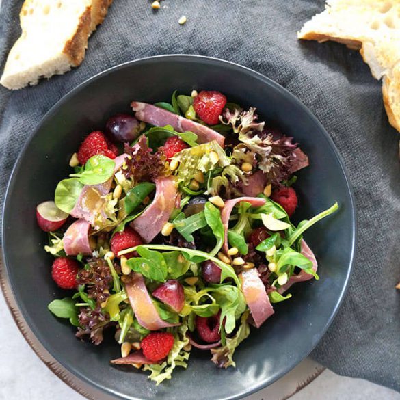 grüner Salat mit gemischten Salatblättern, Roastbeef, Himbeeren, Weintrauben und Honig-Senf Dressing, Pinienkernen und gerösteten Fladenbrot